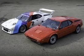 BMW M1 E26 routière rouge et BMW M1 Procar blanche vues trois quarts avant